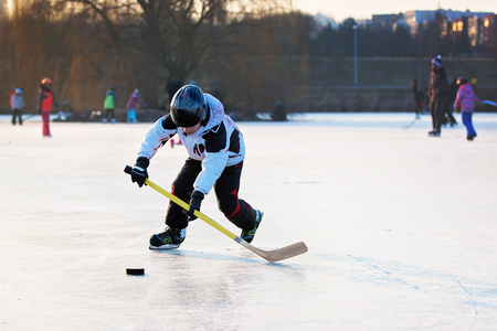 Children, boys, friends and brothers playing hockey and skating in the park on frozen lake,...