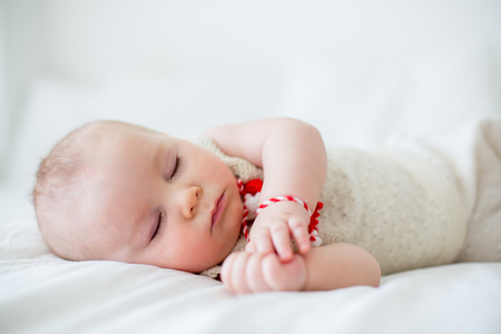 Cute baby toddler boy, sleeping with white and red bracelet.の写真素材