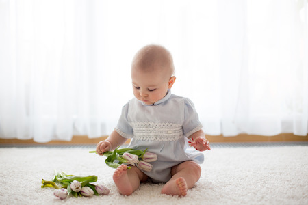 Cute baby boy,  holding bouquet of fresh tulips for mom. Happy Mother's Dayの写真素材