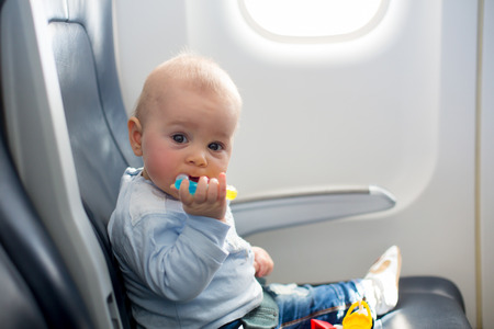 Cute baby boy, playing with toys on board of aircraft, traveling on vacation with parents and siblingsの写真素材