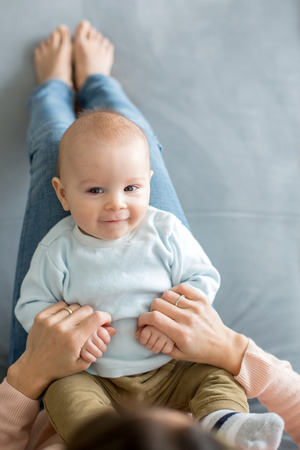 Young mother, holding her toddler boy sitting on a couch, shot from aboveの写真素材