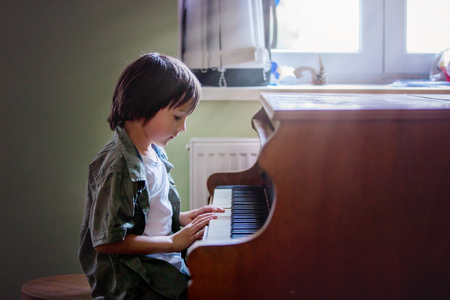 Preschool child, cute boy, playing piano at home, child learning musicの写真素材