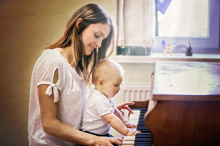 Mother and toddler baby boy, playing piano at home, child learningの写真素材