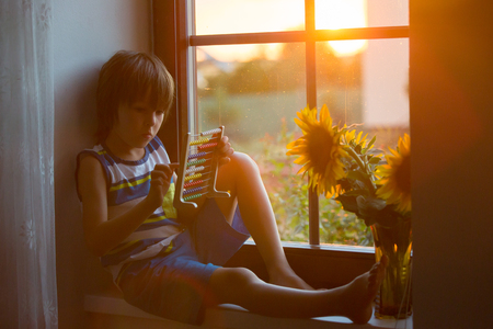 Cute little toddler child, playing with abacus on a window on sunsetの写真素材