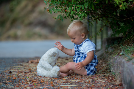 Adorable toddler, playing with teddy bear in the park, summertimeの写真素材