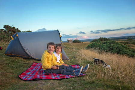 Beautiful family, camping on a hill, enjoying the sunset view in Exmoor National Park on a summer dayの写真素材