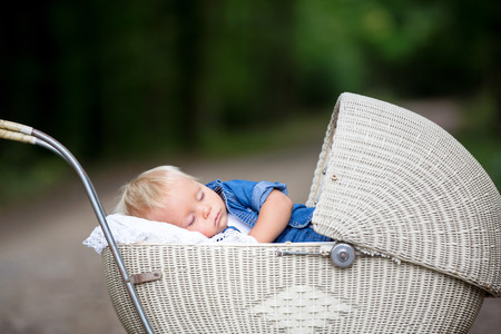 Little newborn baby boy, sleeping in old retro stroller in forest, autumn time. Posed baby in retro pram, baby sleeping, vintage strollerの写真素材