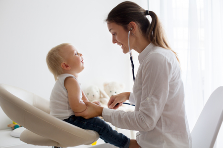 Pediatrician examining baby boy. Doctor using stethoscope to listen to kid and checking heart beatの写真素材