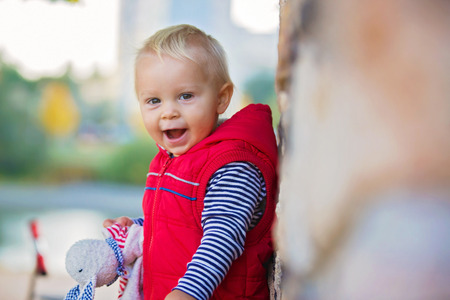 Happy little child, baby boy, laughing and playing with soothing toy in the autumn on the nature walk outdoorsの写真素材
