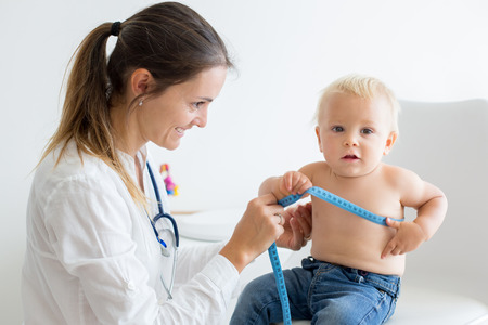 Pediatrician examining baby boy. Doctor using stethoscope to listen to kid and checking heart beatの写真素材