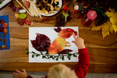 Children, applying leaves using glue, scissors, and paint, while doing arts and crafts in school, autumntimeの写真素材