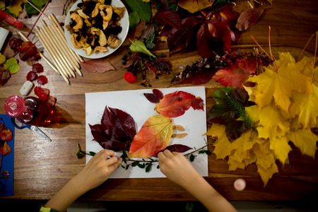 Children, applying leaves using glue, scissors, and paint, while doing arts and crafts in school, autumntimeの写真素材