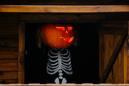 Children having fun with halloween carved pumpkin in a park, wearing scary costumes and playing with...