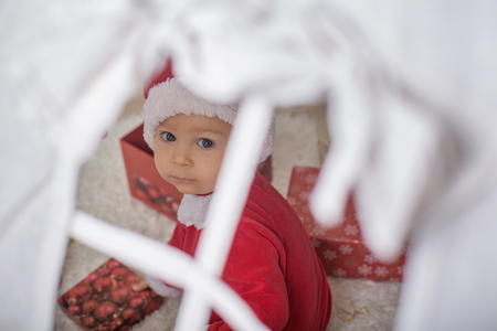 Adorable little toddler baby boy dressed in canta claus costume, playing at home in front of teepee decorated for Christmasの写真素材
