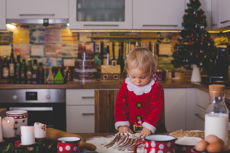 Sweet toddler child, boy, helping mommy preparing Christmas cookies at home in kitchenの写真素材
