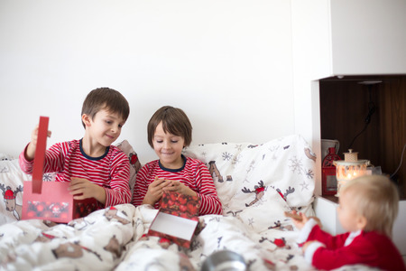 Happy children, opening christmas presents in bed on christmas morningの写真素材