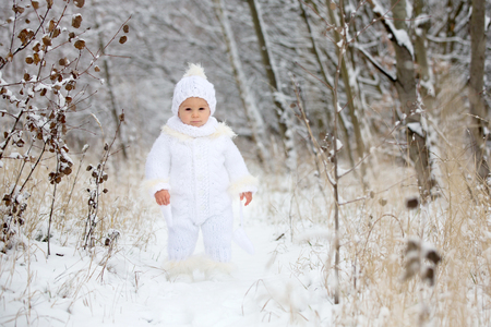 Cute little toddler boy and his older brothers, playing outdoors with snow on a winter day, snowingの写真素材