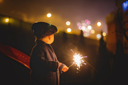 Waist up portrait of happy family celebrating New Year together and lighting sparklers outdoors in gardenの写真素材