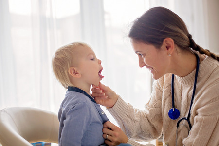 Pediatrician examining baby boy. Doctor using stethoscope for yearly child check up
