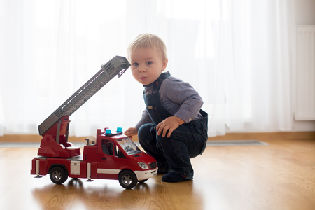 Little toddler boy, playing with fire truck car toy at homeの写真素材