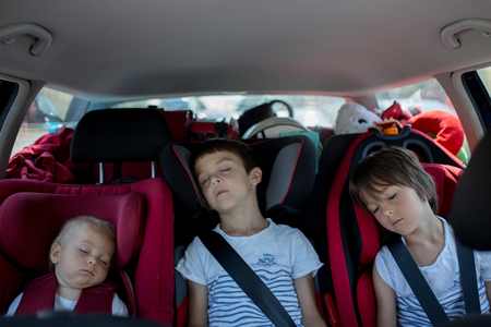 Children travel in car seats in car, going on holidayの写真素材