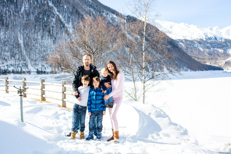 Family, enjoying winter view of snowy mountains and frozen lake on a sunny dayの写真素材