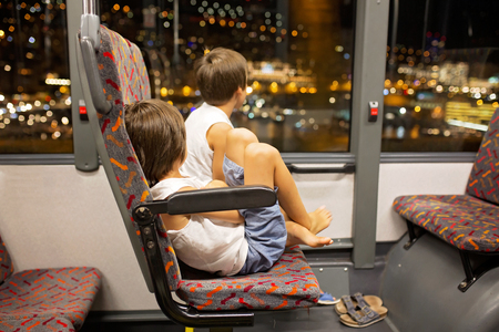 Portrait of children, boys on a bus, enjoying the night view with iluminated streets in Monacoの写真素材