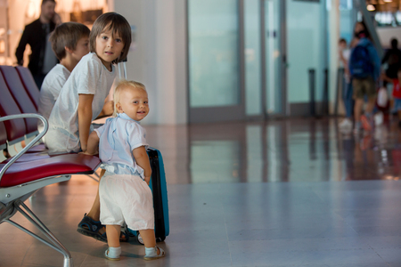 Children, traveling together, waiting at the airport to board the aircraftの写真素材