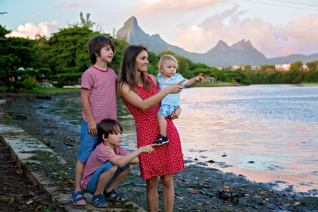 Happy family, parents and children, enjoying aerial view of wild Mauritius mountains, sunset over...