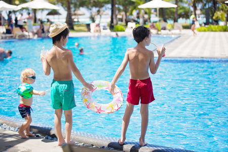 Child with suntan lotion shaped as smile on his back, going at the beach with toys and inflatable ring. Concept for sun protection and skin care for childrenの写真素材
