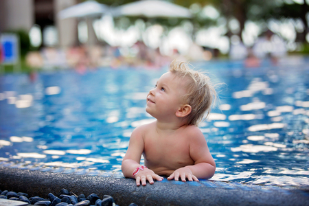 Adorable happy little child, toddler boy, having fun relaxing and playing in a pool on sunny day during summer vacation in resort on Mauritius islandの写真素材