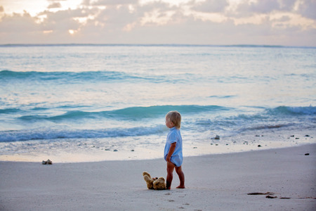 Happy beautiful fashion kid, child, casually dressed, enjoying the sunrise on the beach in Mauritius, family joyful vacationの写真素材