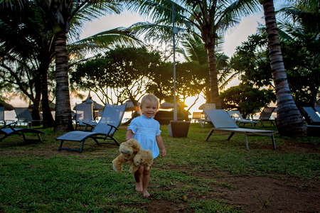 Happy beautiful fashion kid, child, casually dressed, enjoying the sunrise on the beach in Mauritius, family joyful vacationの写真素材