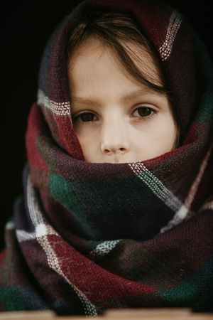 Close up of a child with a scarf wrapped over and around the head, neck and shouldersの写真素材