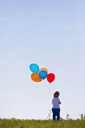 Little boy, toddler, child playing with colorful balloons in the park on kids day, sunny summer afternoon in natureの写真素材
