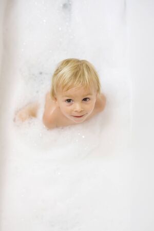 Little boy in bath in the bathroom. Child bathing with a lot of foamの写真素材