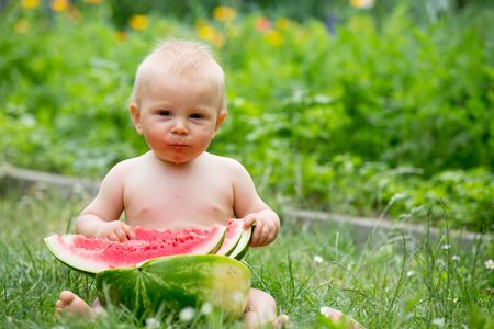 Cute toddler child, baby boy, eating ripe watermelon in garden, tasty fruitsの写真素材