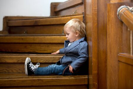 Sad child, sitting on a staircase in a big house, concept for bullying, depression stress or frustrationの写真素材