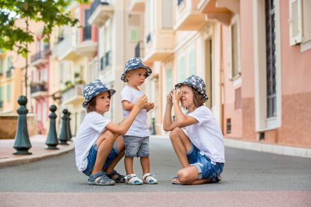 Children taking pictures on a narrow street with houses in Monaco-Ville, Monaco on a cloudy day. Monaco-Ville is one of the four traditional quarters of Monacoの写真素材