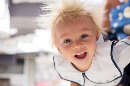Funny two years old child, boy, hanging upside down, smiling happily, mom holding himの写真素材