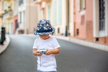 Children taking pictures on a narrow street with houses in Monaco-Ville, Monaco on a cloudy day. Monaco-Ville is one of the four traditional quarters of Monacoの写真素材