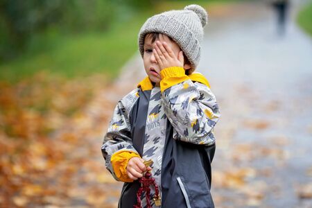 Sweet child, boy, playing in the park on a rainy day, autumn timeの写真素材