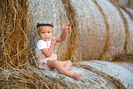 Happy children, playing on haystacks in a field, summertimeの写真素材