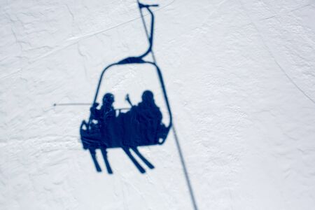 Reflection in the snow of happy people, children and adults, skiing on a sunny day in Tyrol mountains. Kids having fun while skiingの写真素材