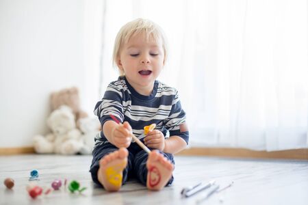 Brothers, playing at home, painting on their feet, tickling, laughing and smilingの写真素材