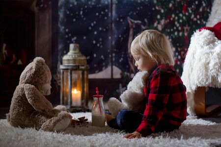 Sweet toddler boy, reading book at home at night on Christmas nightの写真素材