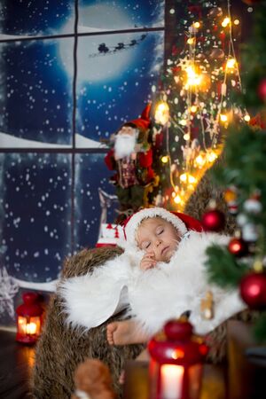 Beautiful toddler child, baby boy, sleeping on Christmas eve at home in cozy atmosphereの写真素材