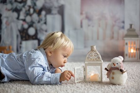 Sweet toddler boylying on the floor at home with candles, waiting for Christmas nightの写真素材