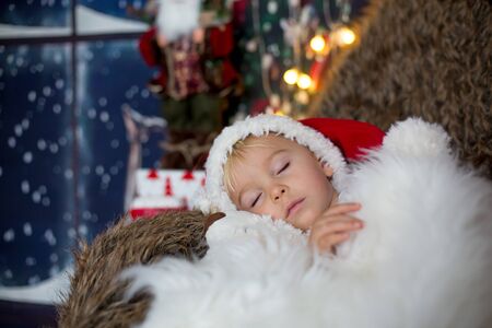 Beautiful toddler child, baby boy, sleeping on Christmas eve at home in cozy atmosphereの写真素材