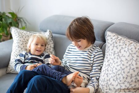 Little toddler and his older brother, having fun at home, tickling and giggle happily